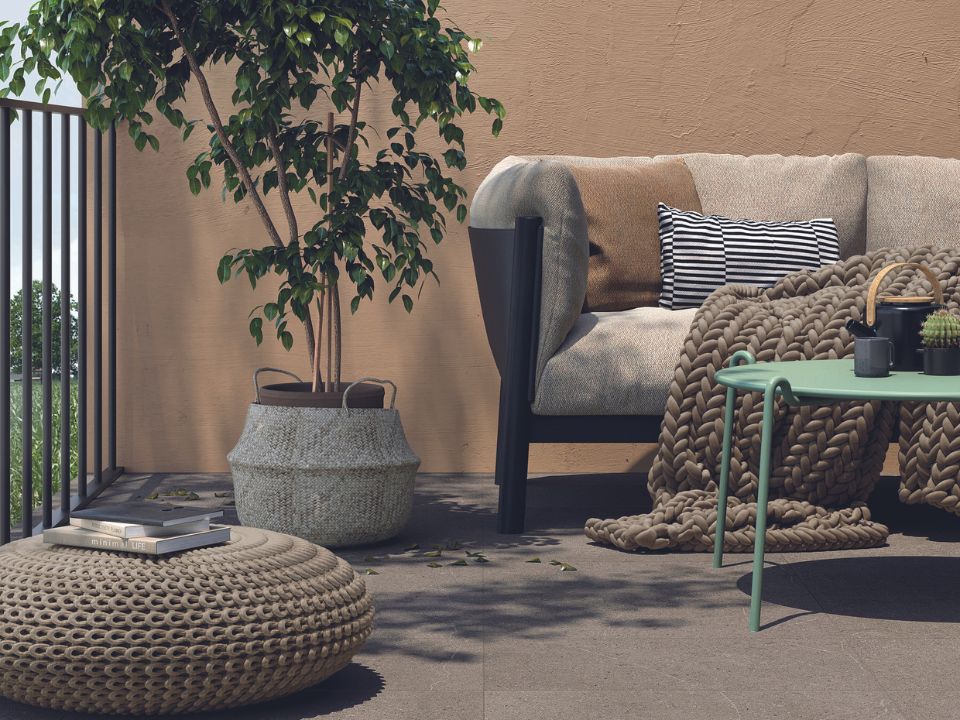 Aménagement extérieur relaxante au décor naturel avec sofa, plantes artificielles et tapis extérieur.