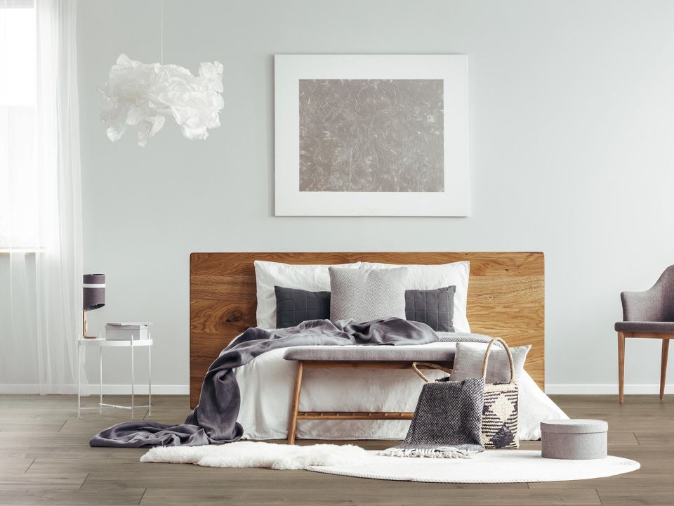 Chambre avec lit de bois et mur blanc