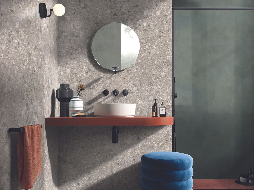 Évier de salle de bain et miroir rond avec un mur de céramique.