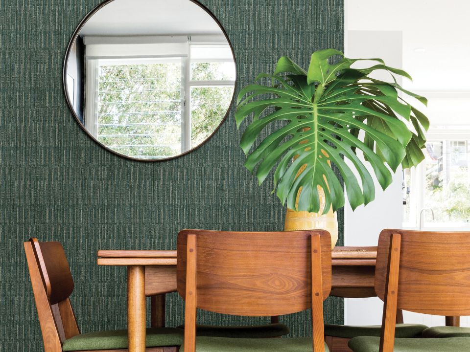 Salle à manger style jungle avec papier peint vert, table en bois et plante.